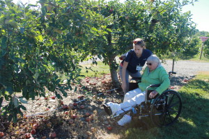 Elant at Fishkill resident Meri Manner prepares to stand up to pick at apple with assistance from occupational therapist Cathryn Steinoff.