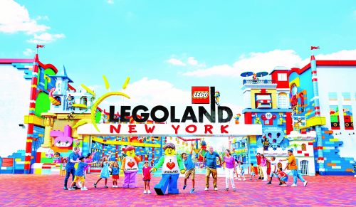 The entrance to LEGOLAND New York Resort with a LEGO figure and visitors.